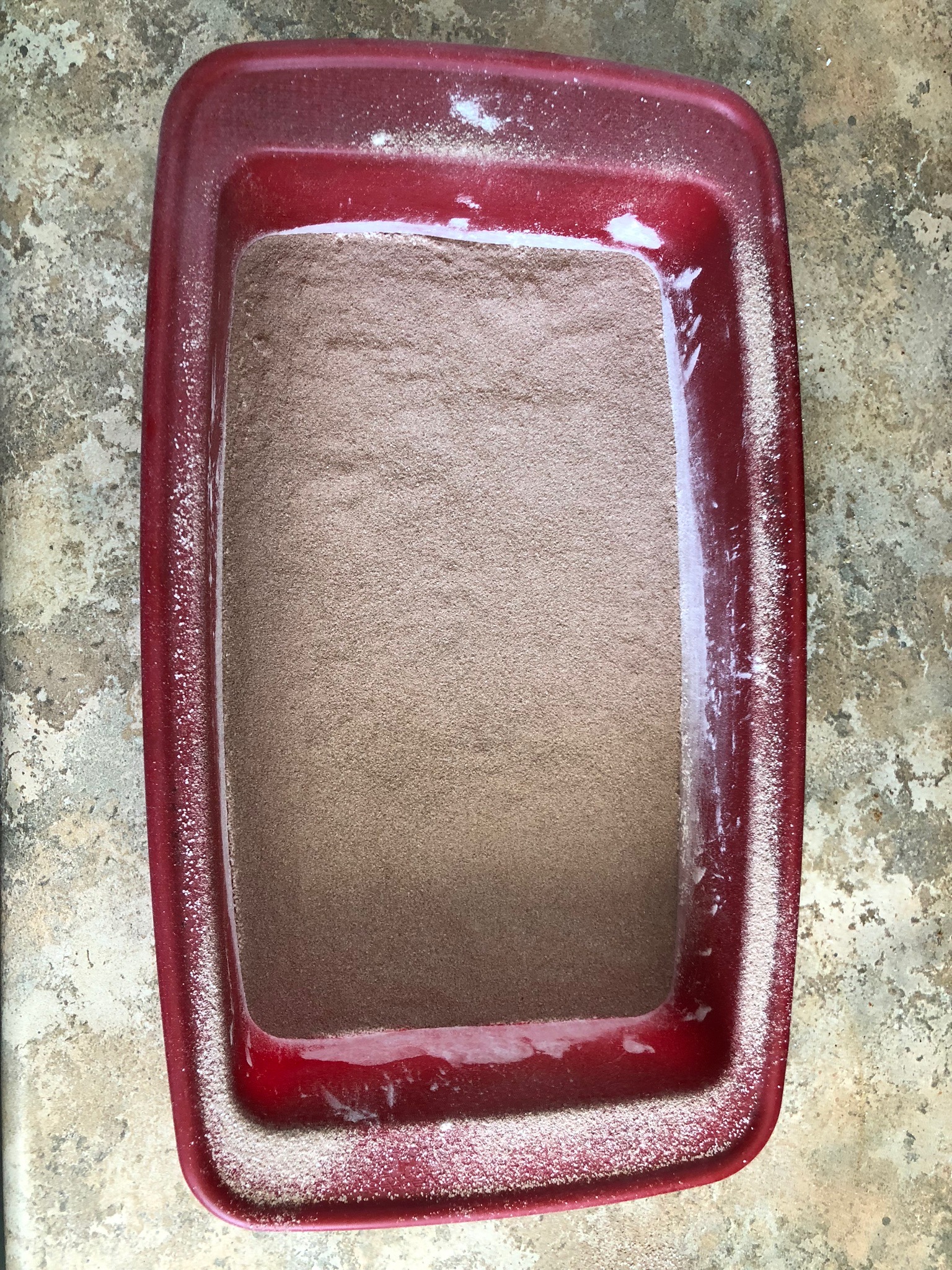A silicone bread pan filled with flour, covered with a thin dusting of hot chocolate.